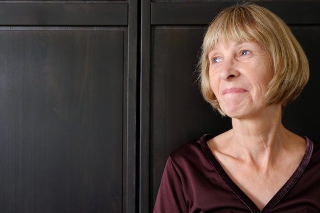 Volwassen vrouw die wegkijkt terwijl ze tegen de kast staat thuis