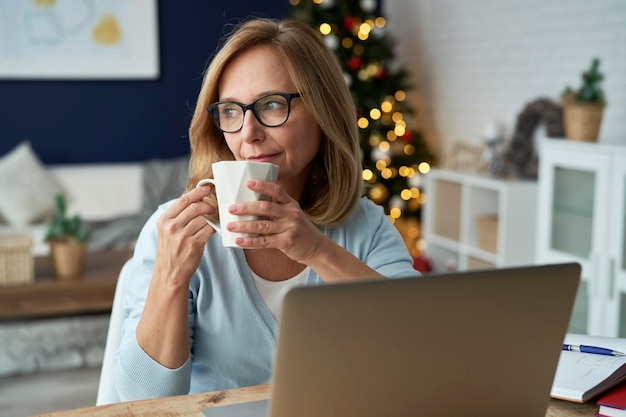 Volwassen vrouw drinkt koffie en kijkt weg.