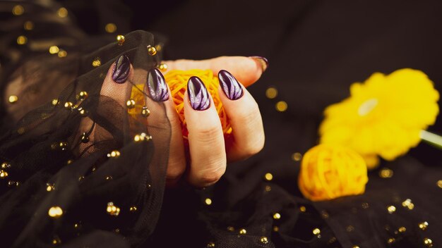 Volwassen vrouw hand met paarse manicure op zwarte achtergrond Crop onherkenbaar persoon met ontwerp op nagels Concept van zorg en schoonheid