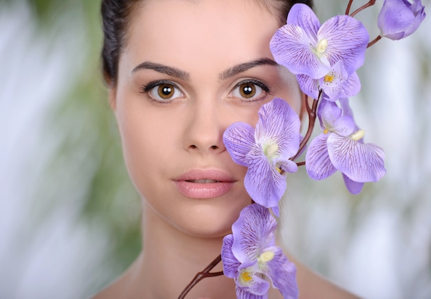 Volwassen vrouw met mooi gezicht en paarse bloemen.