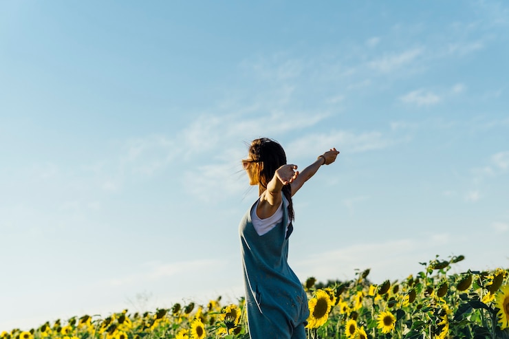 Volwassen vrouw met open armen in een veld met zonnebloemen. gevoel van vrijheid