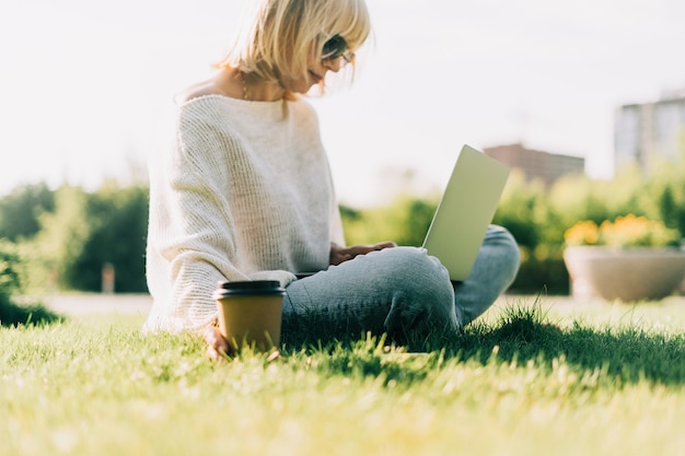 Volwassen vrouw op gras met laptop