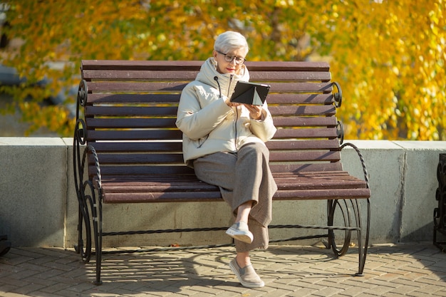 volwassen vrouw zit op een bankje met een tablet