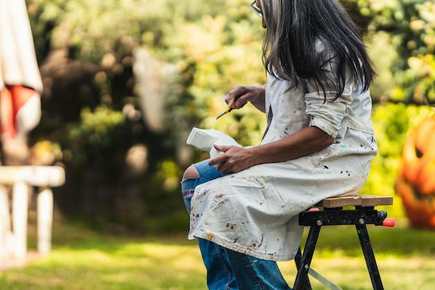 Volwassen vrouw zittend op een tuin bezig met het vormgeven van een stuk polystyreen