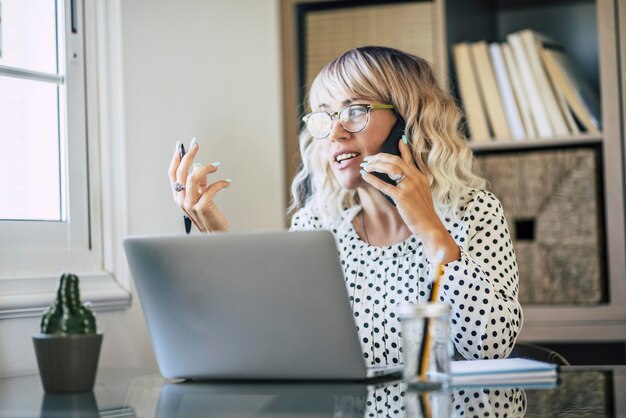 Volwassen vrouwelijke ondernemer aan het werk druk in telefoongesprek en het uitleggen van oplossingen aan collega's op een externe kantoorwerkplek Online job zakelijke activiteit Een zakenvrouw die apparaatverbindingen gebruikt