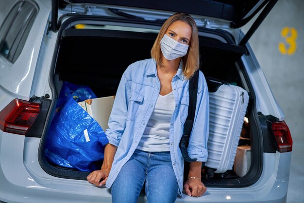 volwassen vrouwelijke toerist die een masker draagt vanwege covid-19-procedures op de ondergrondse parkeerplaats van de luchthaven