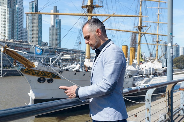 Foto volwassen zakenman buitenshuis staande telefoon controleren