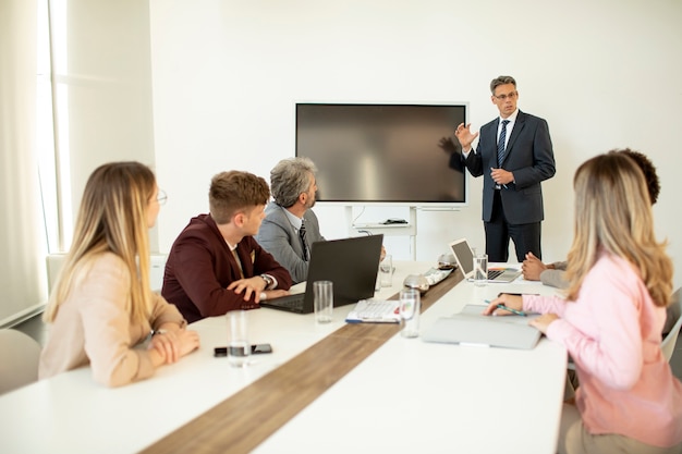 Volwassen zakenman strategie uit te leggen aan groep multi-etnische zakenmensen terwijl u werkt aan een nieuw project op kantoor