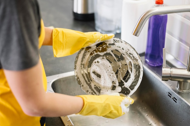 Volwassene met handschoenen afwassen