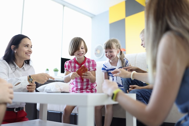 Volwassenen en kinderen zitten rond de tafel met speelkaarten en lachen vrolijk