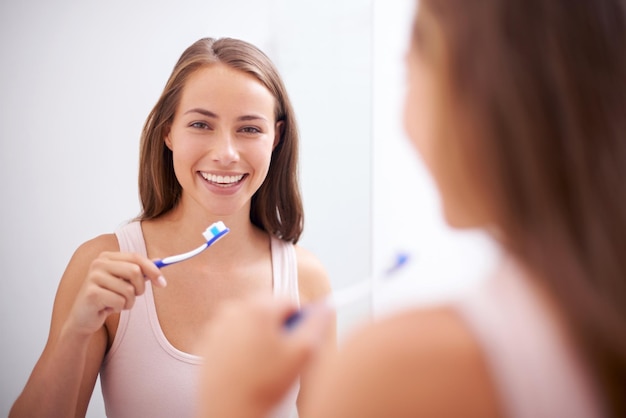 Voor haar glimlach zorgen Een jonge vrouw die haar tanden poetst