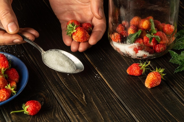 Voor het bereiden van een zoete compote van verse aardbeien en munt moet je suiker toevoegen