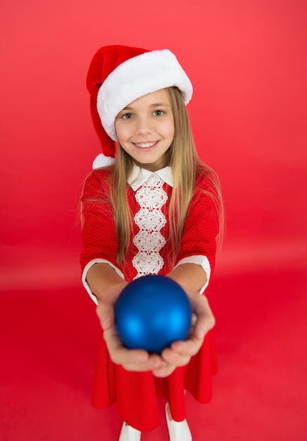 Voor jou. Gelukkig kind rood kostuum houdt kerstversieringen close-up selectieve aandacht. Winkel voor decoraties. Maak unieke decoraties. Kerst bal decor. Ideeën voor het decoreren van kerst voor de kinderkamer.