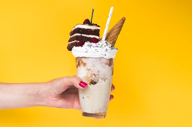 Vooraanzicht dat van hand een milkshake met gele achtergrond houdt