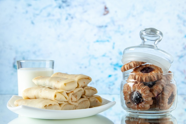 vooraanzicht gerolde zoete pannenkoeken met melk en koekjes op lichtblauwe achtergrond bloem maaltijd cake ontbijt kleur ochtend taart eten