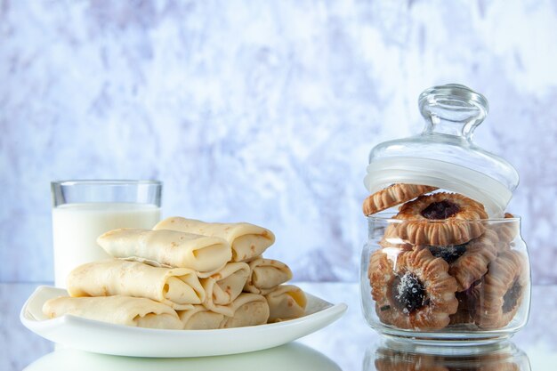 vooraanzicht gerolde zoete pannenkoeken met melk en koekjes op lichte achtergrond suikertaart maaltijd ontbijt ochtend eten kleur taarten