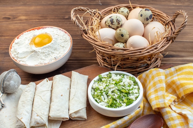 vooraanzicht greens pitabroodjes met eieren en bloem op bruine achtergrond vlees koken bak olie cake gebak deeg maaltijd