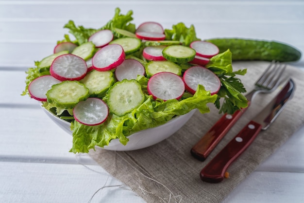 Vooraanzicht Groentesalade met radijs, komkommer en sla in een slakom, plat leggen.