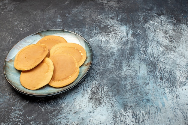 Vooraanzicht heerlijke kleine pannenkoeken binnen plaat op grijze achtergrond honing suiker ontbijt ochtend eten familie bak deeg gelei vrije ruimte