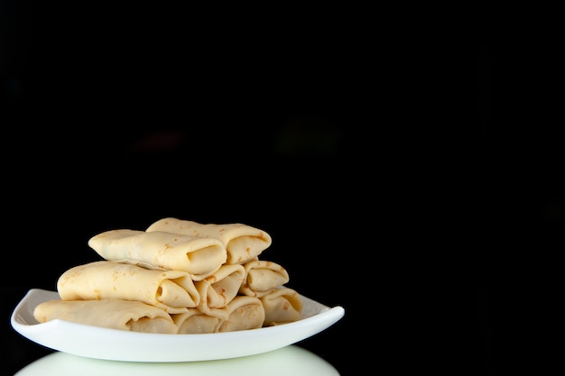 vooraanzicht heerlijke zoete pannenkoeken gerold binnen plaat op zwarte achtergrond ontbijt maaltijd cake suiker melk eten ochtend kleur