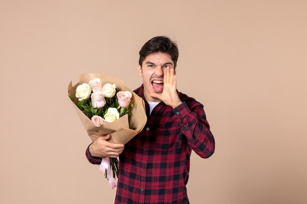 Vooraanzicht jong mannetje dat mooie bloemen op bruine muur houdt