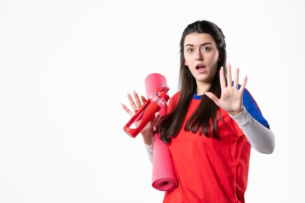 Vooraanzicht jong wijfje in sportkleren met de witte muur van de yogamat