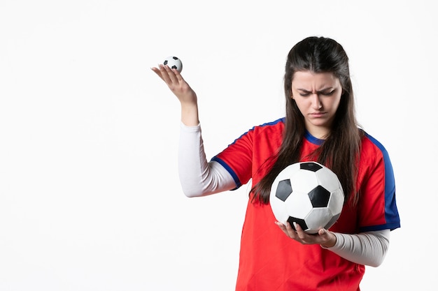 Vooraanzicht jong wijfje in sportkleren met voetbal op witte muur