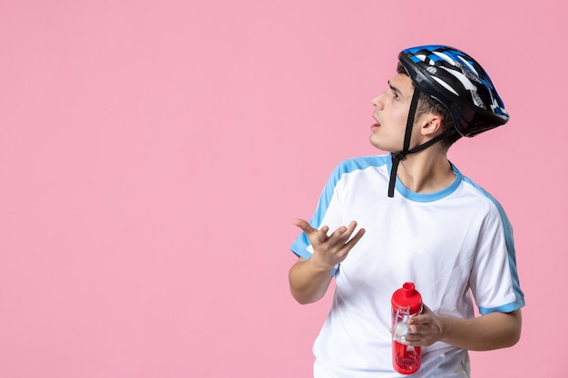 Vooraanzicht jonge atleet in sport kleding helm en fles water te houden