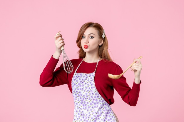 vooraanzicht jonge huisvrouw met garde en houten lepel op roze achtergrond keuken koken uniform horizontale vrouw taart cake