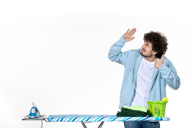 Foto vooraanzicht jonge man achter strijkplank op witte achtergrond kleur man schoonmaak huishoudelijk werk was foto's ijzer kleren