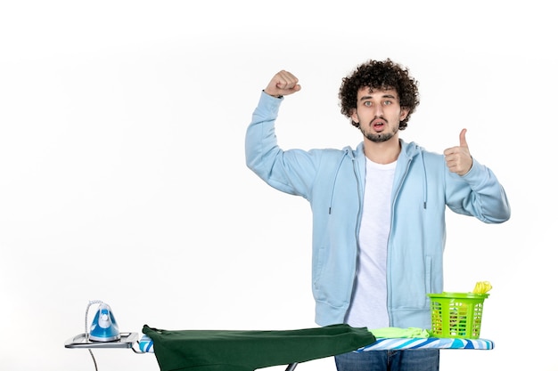 vooraanzicht jonge man achter strijkplank vreugde op witte achtergrond huishoudelijk werk strijken wasgoed kleren schoonmaken emotie man kleur