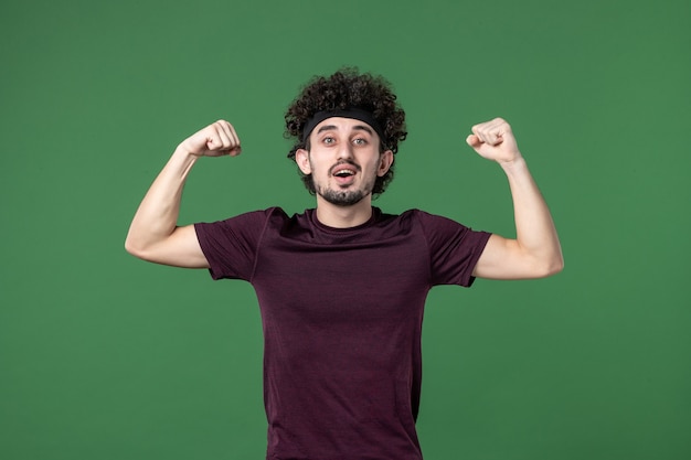 vooraanzicht jonge man buigen op groene achtergrond kleur sport sportschool training atleet hardlopen gezondheid model emotie