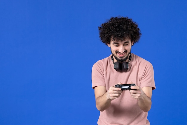 vooraanzicht jonge man die videogame speelt met zwarte gamepad op blauwe achtergrond virtuele jeugdbank volwassen voetballer winnende vreugde tieners