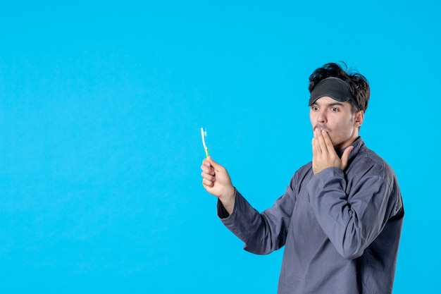 vooraanzicht jonge man in pyjama met tandenborstel met verbaasde uitdrukking op blauwe achtergrond droom nachtmerrie nacht kleur wakker schoon mens