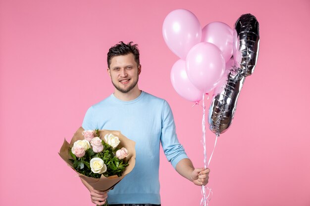 vooraanzicht jonge man met bloemen en ballonnen als maart aanwezig op roze achtergrond gelijkheidsdatum vrouwendag huwelijk vrouwelijk sensueel liefde