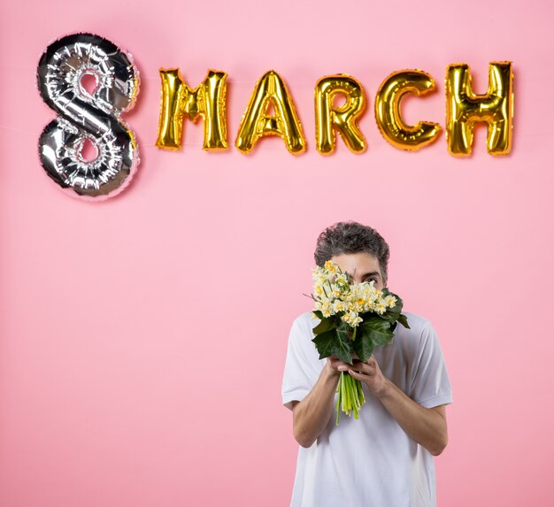 vooraanzicht jonge man met bloemen voor vrouw met maart versierd roze achtergrond gelijkheid vrouwendag vakantie emotie sensueel feest glamour