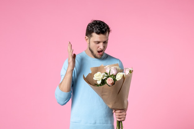 vooraanzicht jonge man met boeket van mooie bloemen op roze achtergrond funpark sensuele vrouwendag maart vrouwelijk datum huwelijk liefde