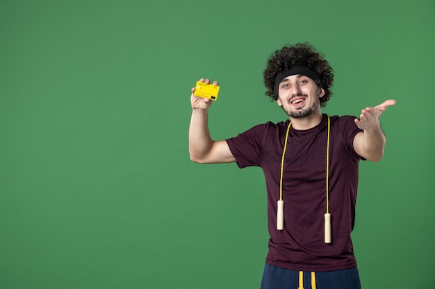 vooraanzicht jonge man met gele bankkaart op de groene achtergrond model yoga gezondheid training levensstijl sport atleet sportschool geld