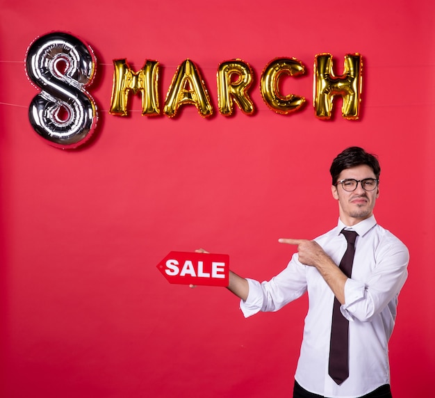 vooraanzicht jonge man met maart decoratie met verkoop naambord op rode achtergrond winkelen vakantie vrouw dames dag sensuele mode kleur