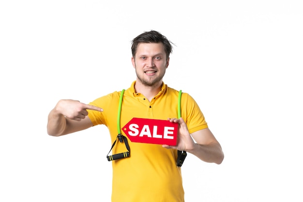 vooraanzicht jonge man met rode verkoop geschreven naambord op witte achtergrond baan sport mens winkelen werknemer sportschool uniform geld