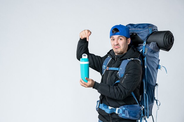 vooraanzicht jonge man met rugzak en thermos op witte achtergrond sneeuw bos natuur campagne koude lucht tent kamp bergen