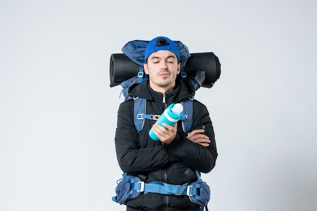 vooraanzicht jonge man met rugzak met thermos op witte achtergrond campagne sneeuw lucht natuur berg koud bos