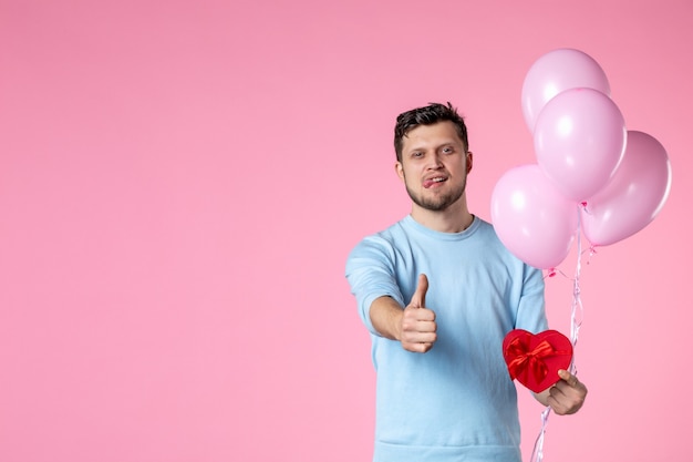 vooraanzicht jonge man met schattige roze ballonnen en hartvormig cadeau op roze achtergrond liefde sensuele gelijkheid vrouwendag maart vrouwelijk park datum leuk huwelijk