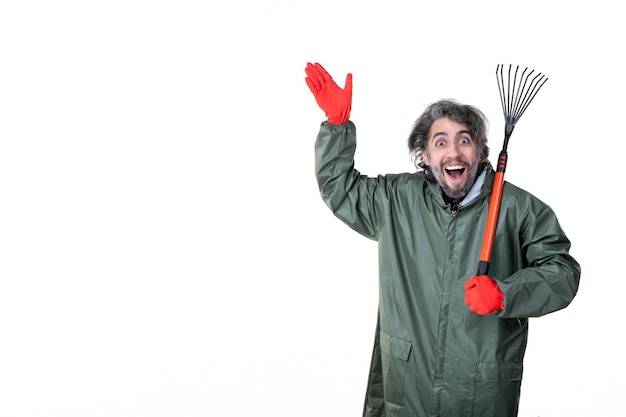 Vooraanzicht jonge man met tuinventilator hark op een witte muur boom plant bodem groene bloem baan veld kleuren