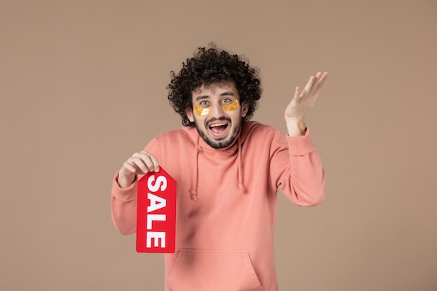 vooraanzicht jonge man met verkoop naambordje op bruine achtergrond gezichtssalon huid winkelen therapie spa huidverzorging
