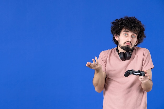 vooraanzicht jonge man met zwarte gamepad op blauwe achtergrond tiener jeugd vreugde voetbal winnende speler sofa volwassen virtueel