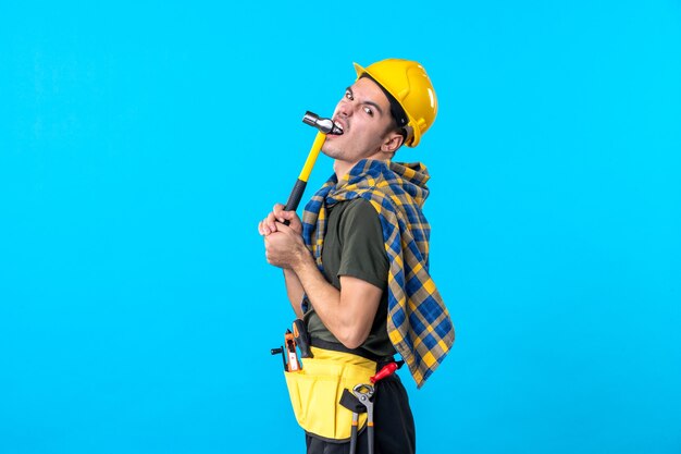 vooraanzicht jonge mannelijke bouwer met hamer op blauwe achtergrond werknemer huis baan gebouw architectuur constructeur