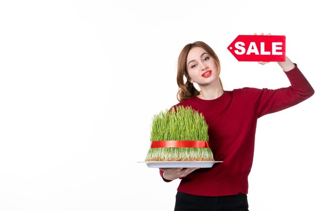 vooraanzicht jonge vrouw met grote novruz semeni en rood verkoop naambordje op witte achtergrond diner kleuren uitvoerder etniciteit winkelen lente etnisch