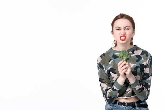 Vooraanzicht jonge vrouw met kleine groene broccoli op een witte achtergrond lunch maaltijd salade schotel voedsel menselijk dieet gezondheidszorg