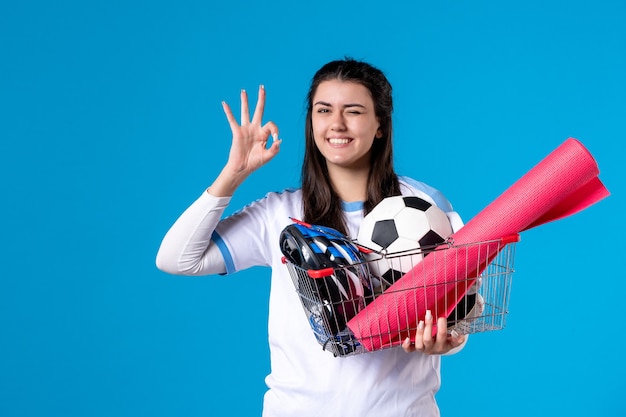 Vooraanzicht jonge vrouw met mand vol sport dingen blauwe muur